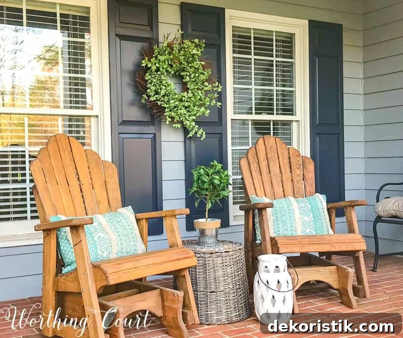 pair of wood stained adirondack chairs on front porch with gray siding