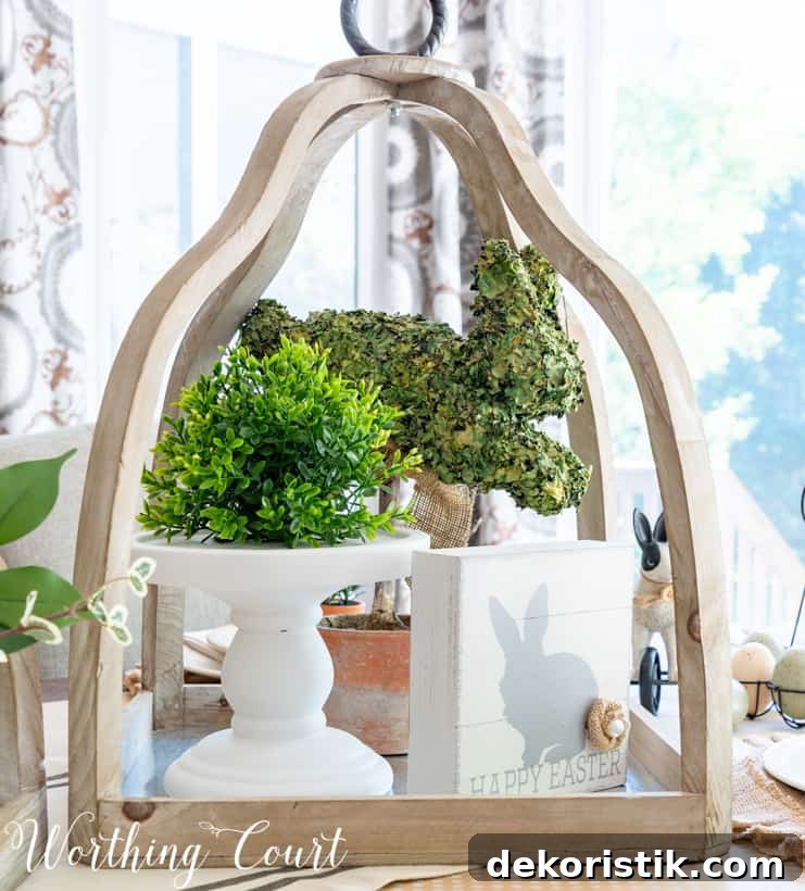 Large open lantern decorated for Easter with a white cake stand in it and a green potted plant on the stand.