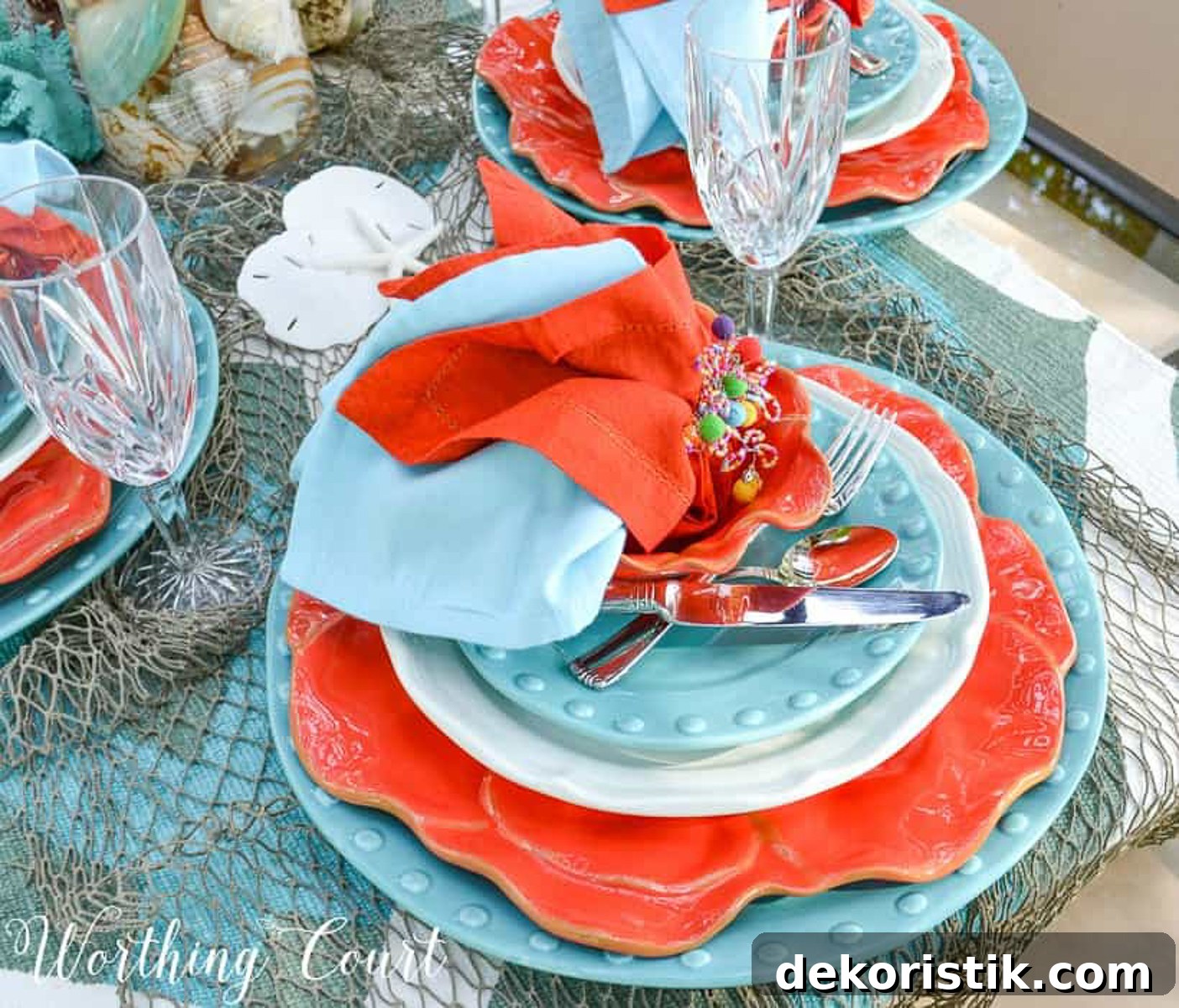 outdoor dining table set with a coastal theme using blue and coral dishware and coastal accessories