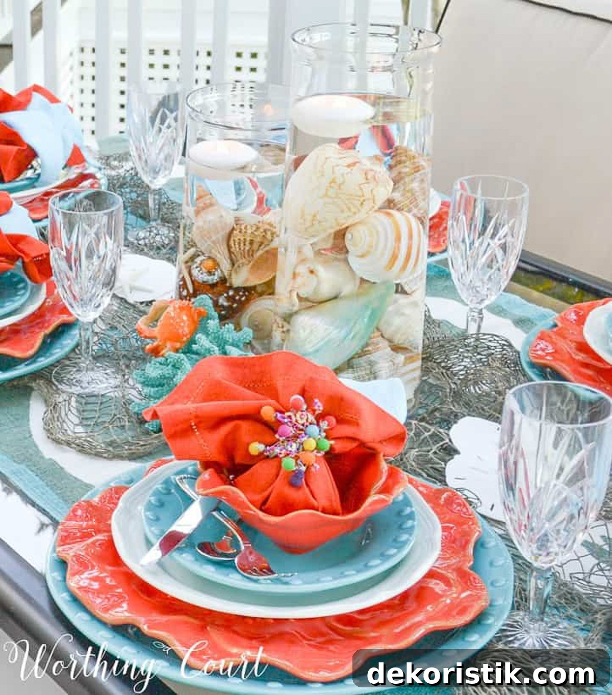 outdoor dining table set with a coastal theme using blue and coral dishware and coastal accessories
