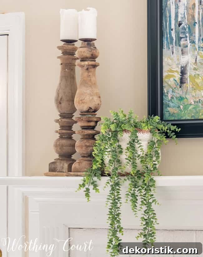 Natural wood candlesticks and trailing greenery on a mantel.