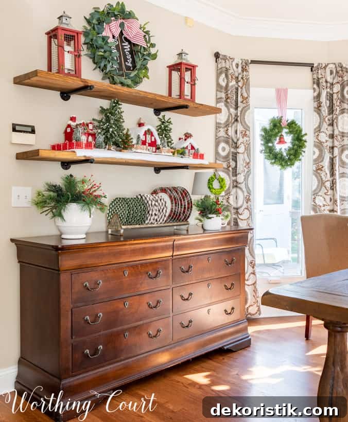 Shevles decorated for Christmas with a Christmas village and plaid dishes.