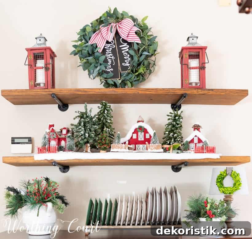 Open shelving unit in the dining room with a Christmas wreath, a little village and Christmas plates.
