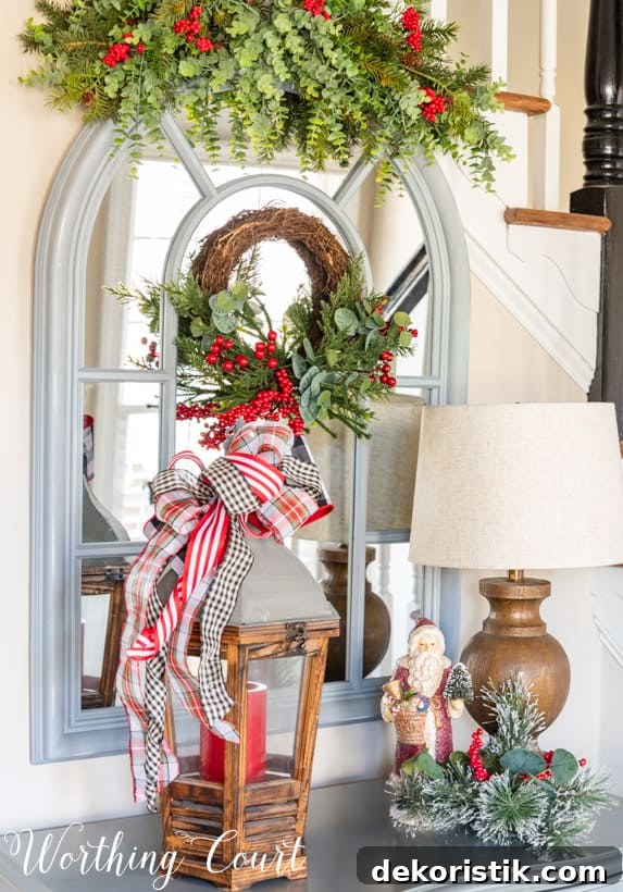 Arched mirror topped with a sway of faux greenery and red berries for Christmas.