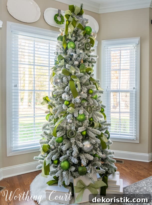 Flocked Christmas tree with green and silver ornaments and ribbon.
