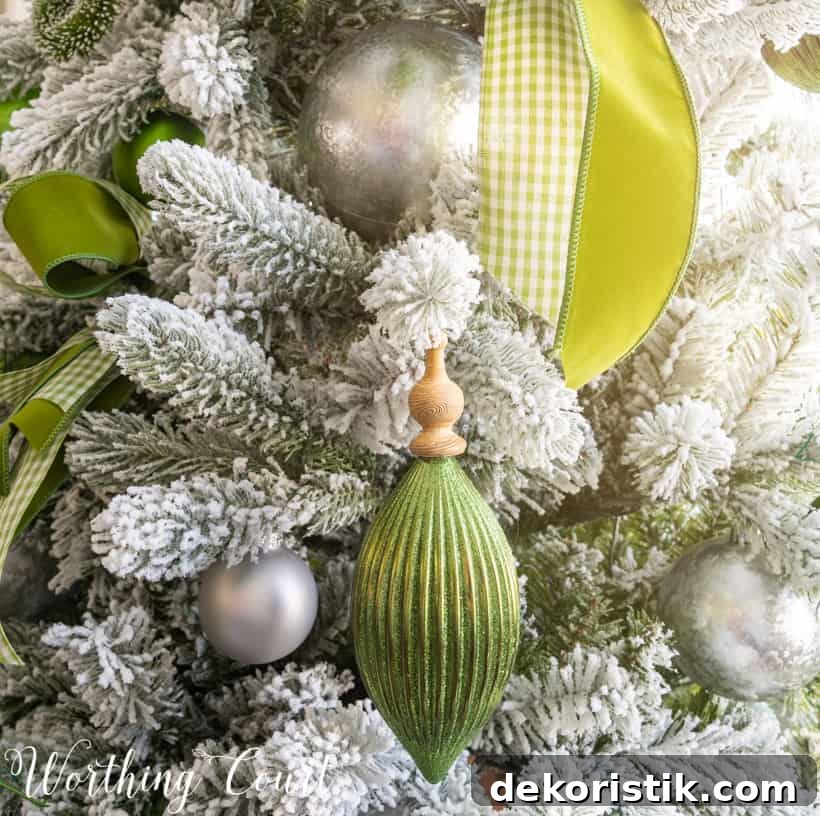 A soft green ornament with a wooden top beside green ribbon on the tree.