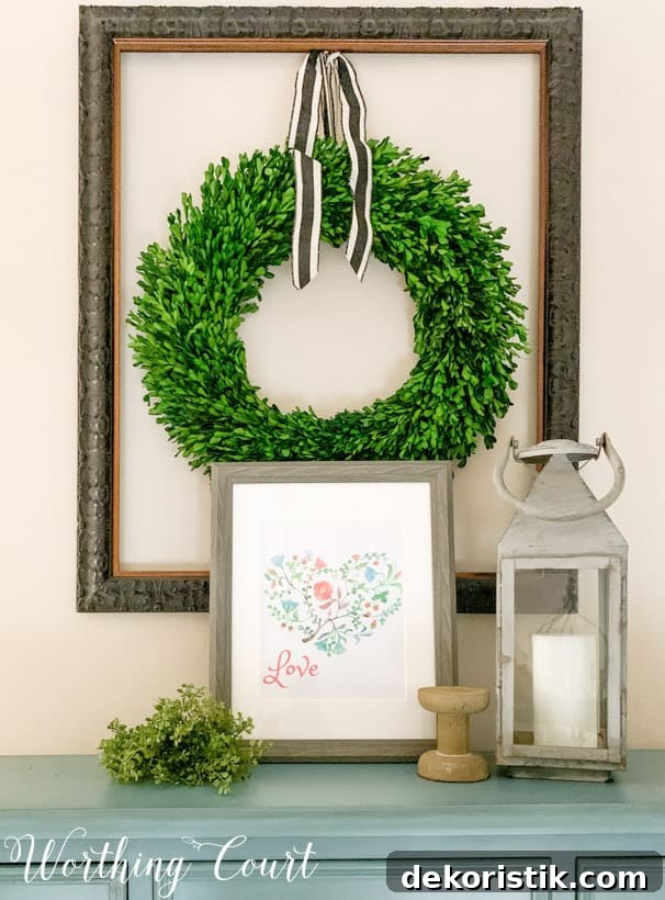 The Valentines printable on a side table with a green wreath on the wall above it.