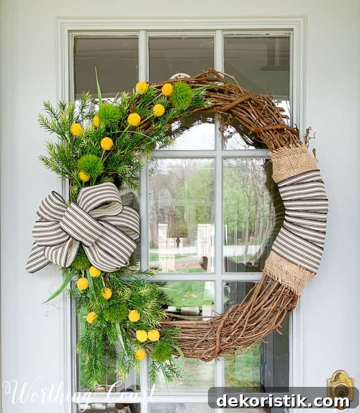 The grapevine wreath with yellow flowers and a black and white bow.