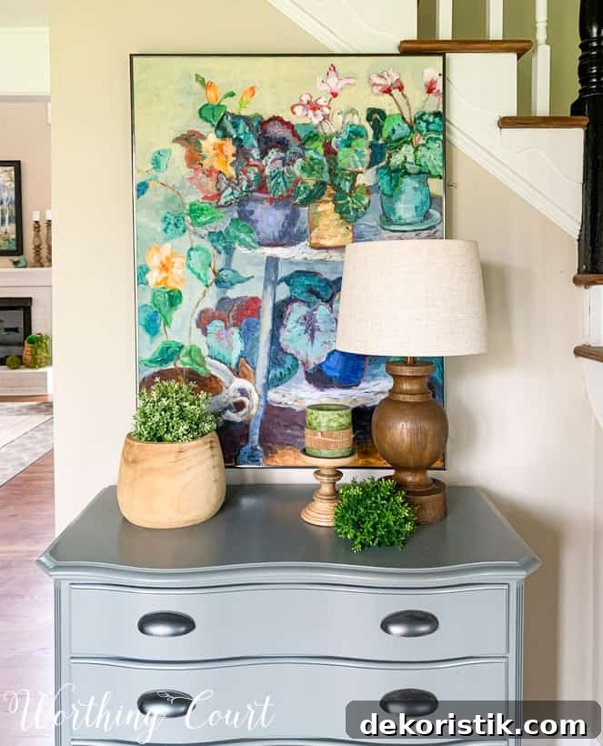 colorful oil painting hanging above gray chest