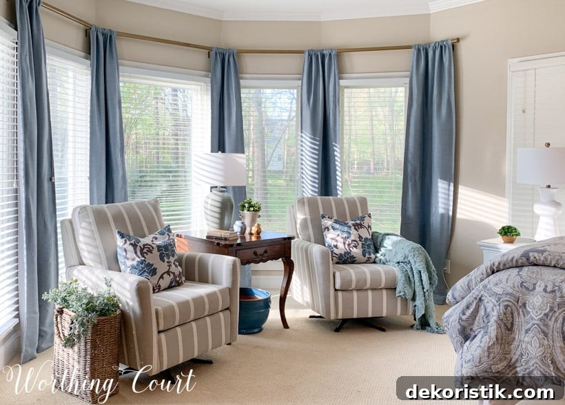 Bedroom bay window sitting area with chairs and blue draperies.