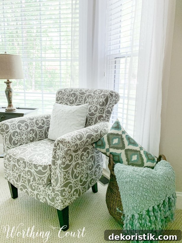 Gray and white arm chair with a large basket beside it filled with blankets and pillows.