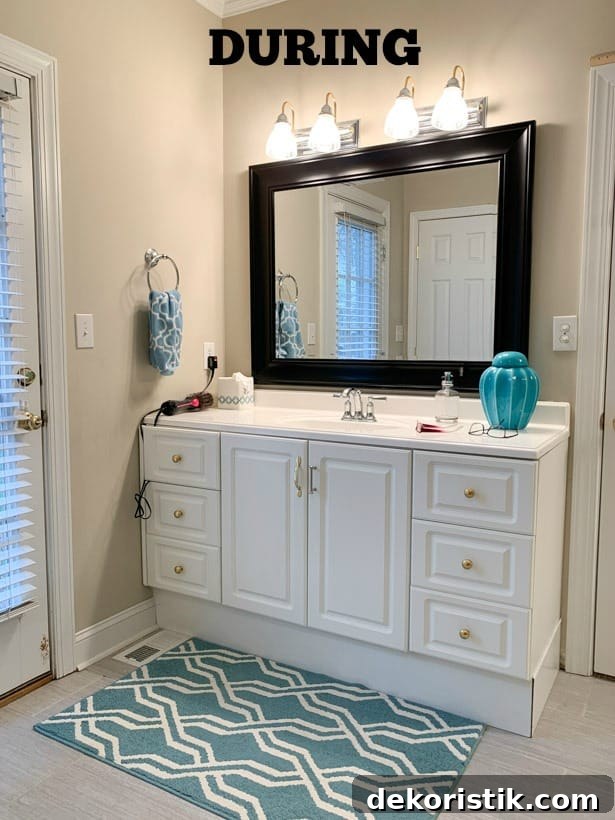 A look at the bathroom during the renovation with a white vanity and blue and white rug.