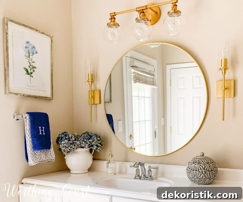 A round gold mirror is above the bathroom sink.