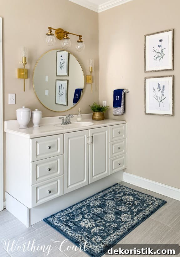 There is a blue and white mat, white vanity and gold accessories in the bathroom.