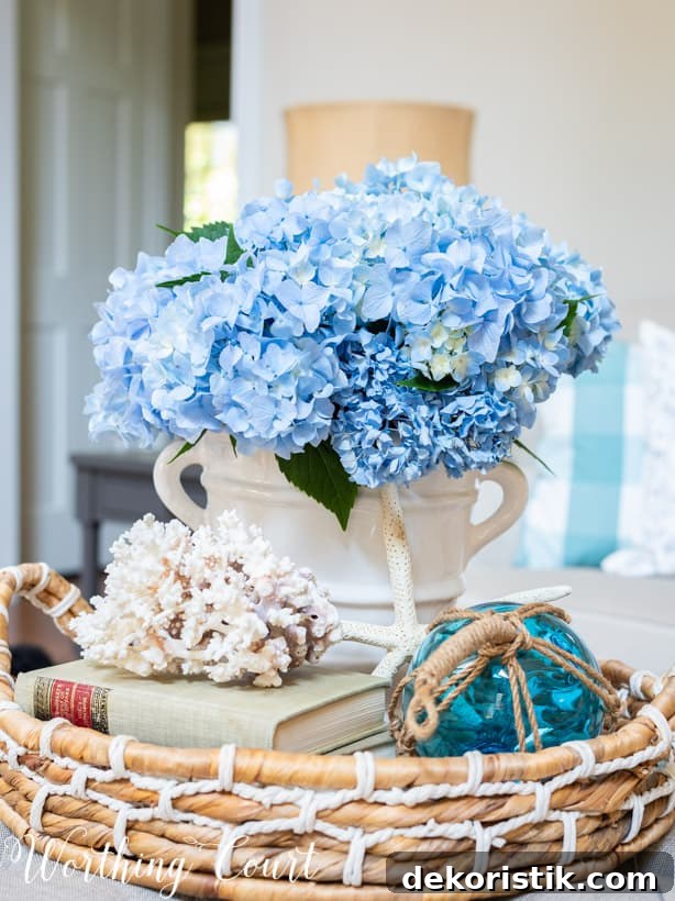 Seashells, a book, flowers and blue glass in the vignette on the coffee table.