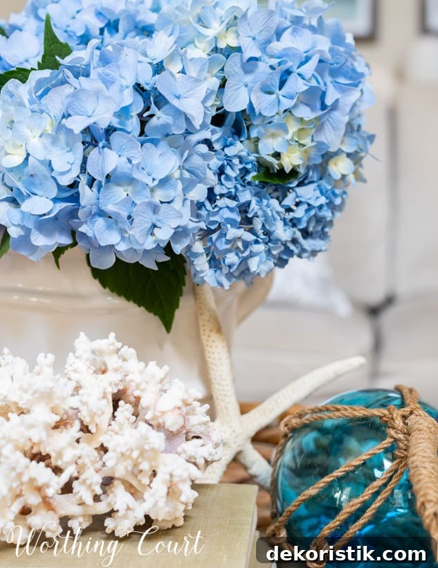 blue hydrangeas in a white vase in a wicker tray on coffee table.