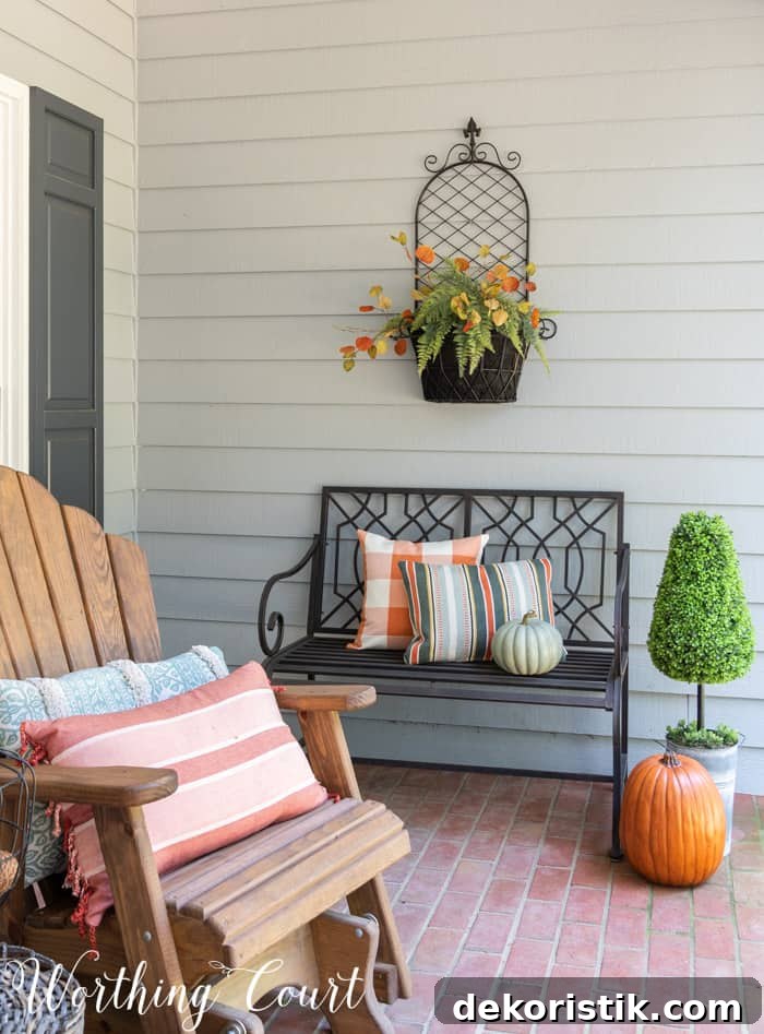 black outdoor bench with fall pillows and pumpkins