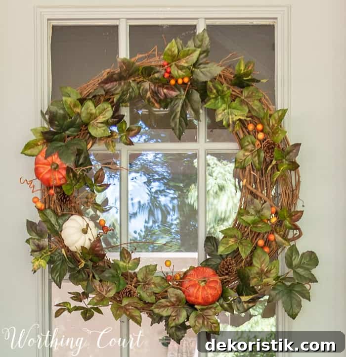 fall wreath with greenery, pumpkins and berries