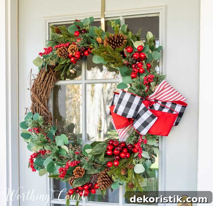 Christmas wreath with black white and red ribbon and greenery and red berry picks