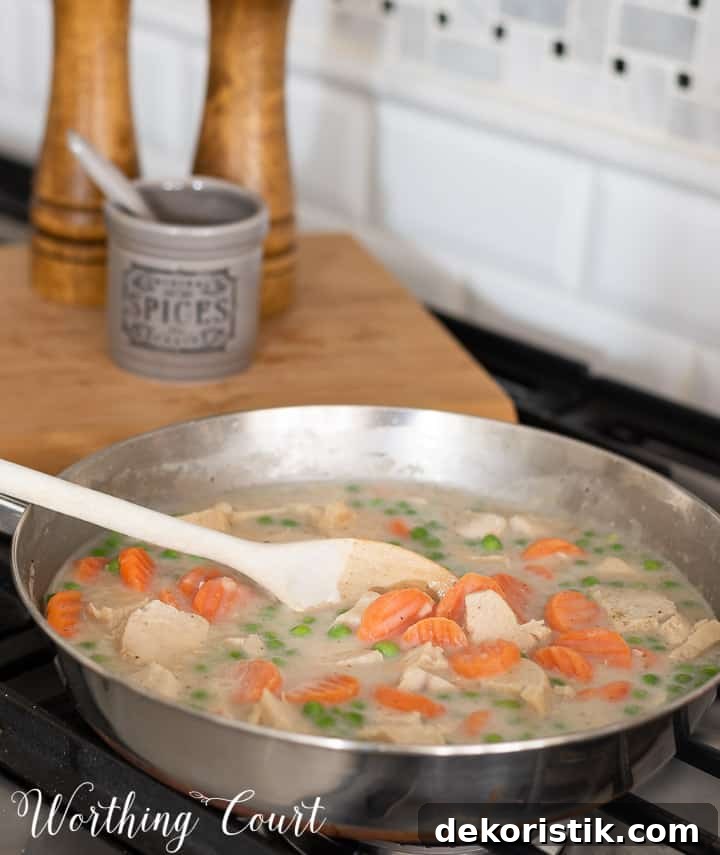 ingredients for chicken pot pie cooking in a skillet on the stove