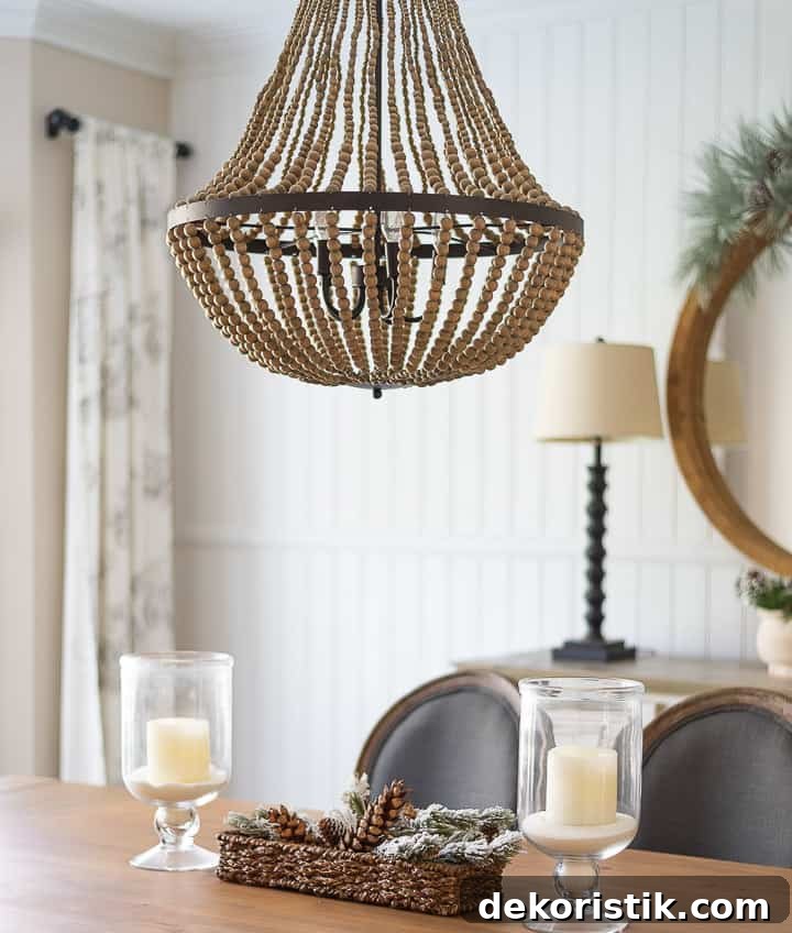 beaded chandelier above dining room table with a pair of glass lanterns for the centerpiece