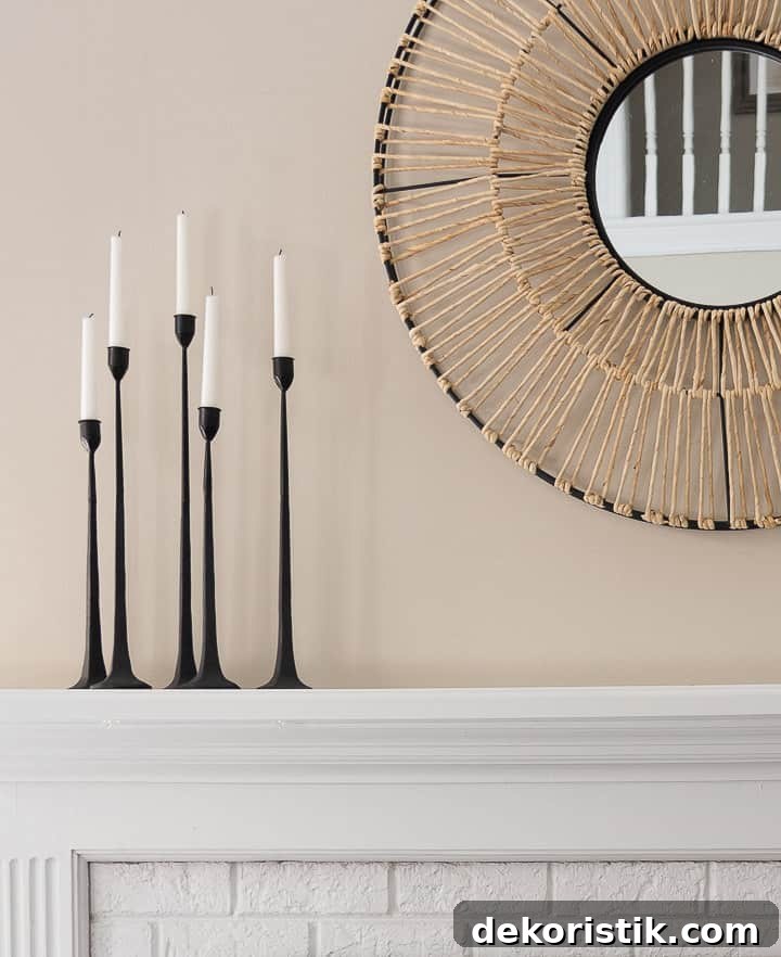 grouping of black candlesticks beside a white mirror on a white fireplace mantel