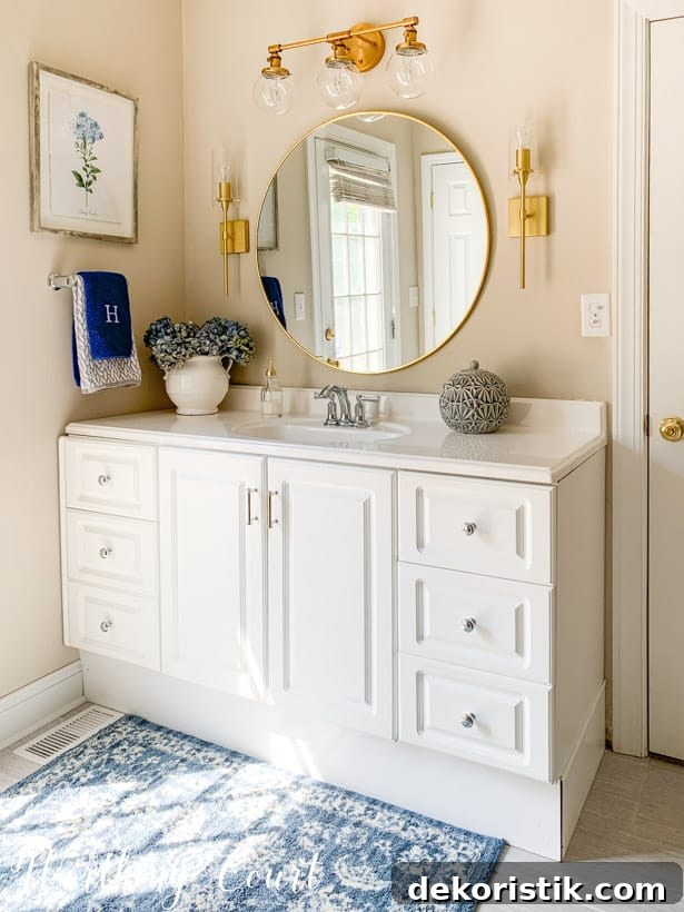 white bathroom vanity with round mirror, gold lights and accessories