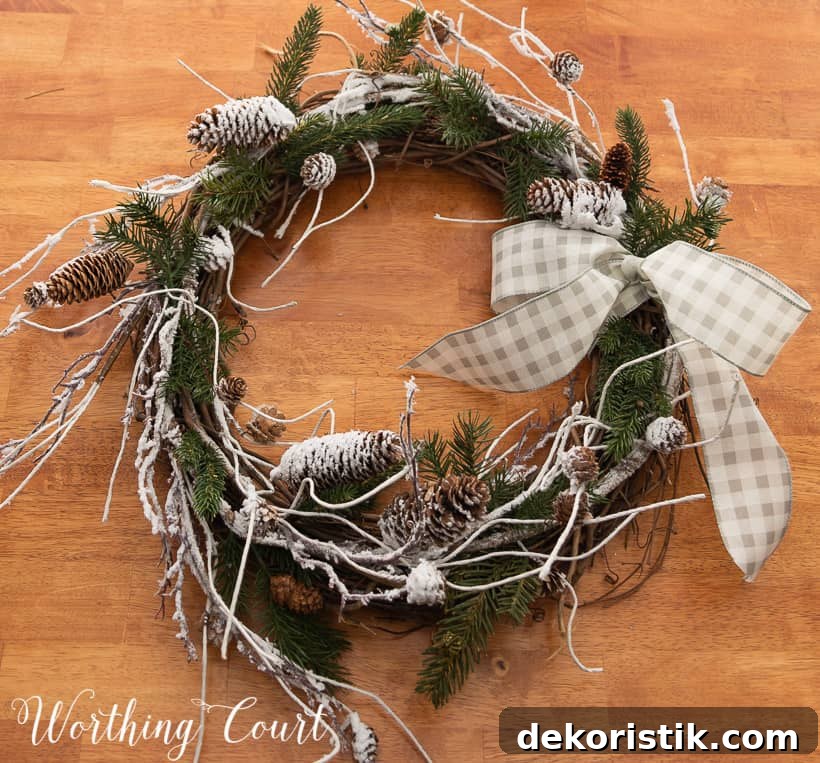closeup of a winter wreath with snowy branches, pine branches and a bow