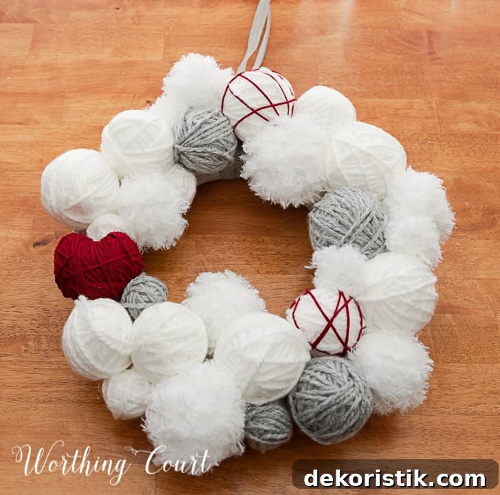 Valentine's Day wreath made with styrofoam balls covered with white and gray yarn and a heart cutout wrapped with red yarn