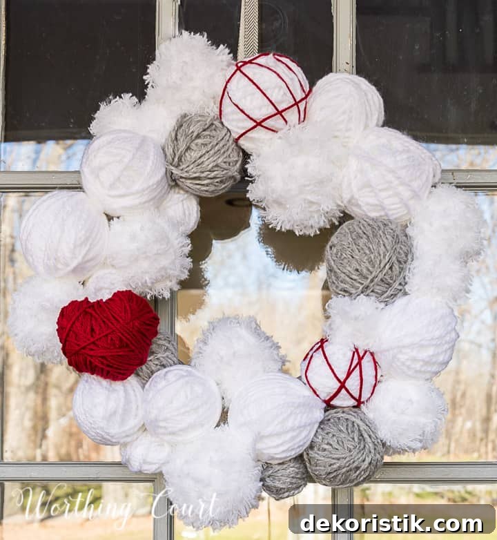 Valentine's Day wreath made with styrofoam balls covered with white and gray yarn and a heart cutout wrapped with red yarn