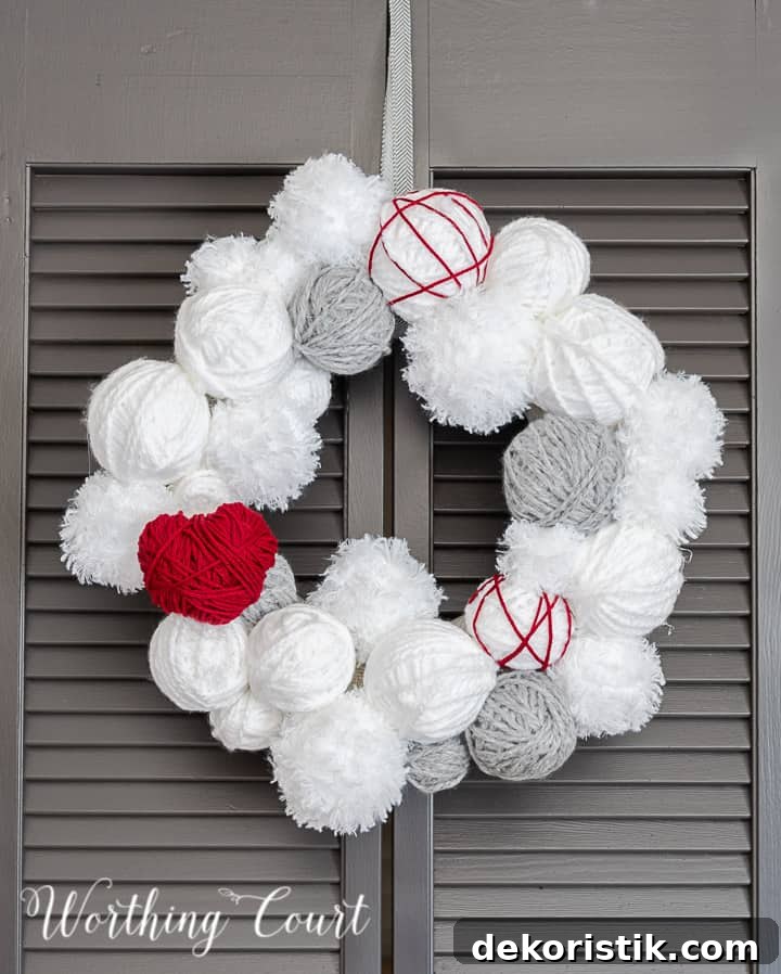 Valentine's Day wreath made with styrofoam balls covered with white and gray yarn and a heart cutout wrapped with red yarn