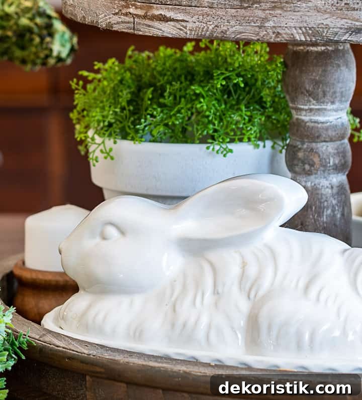 bottom level of a tiered tray with a white bunny and faux greenery