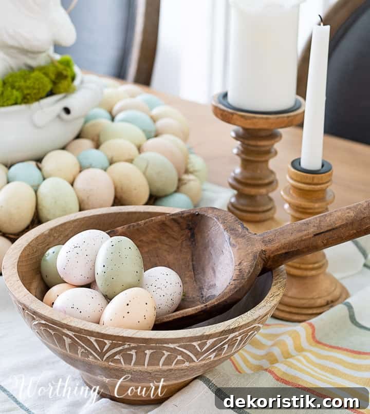 Partial view of Easter centerpiece with white ceramic bunny in the middle of an egg wreath and a wood bowl filled with faux Easter eggs