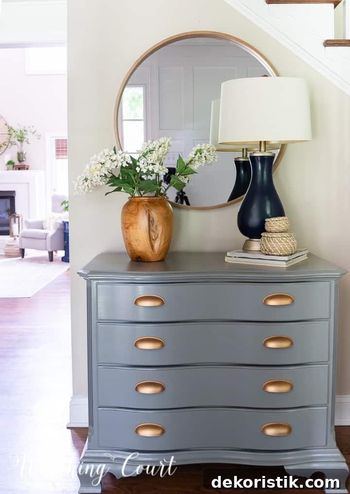 painted gray chest with gold handles and a round mirror