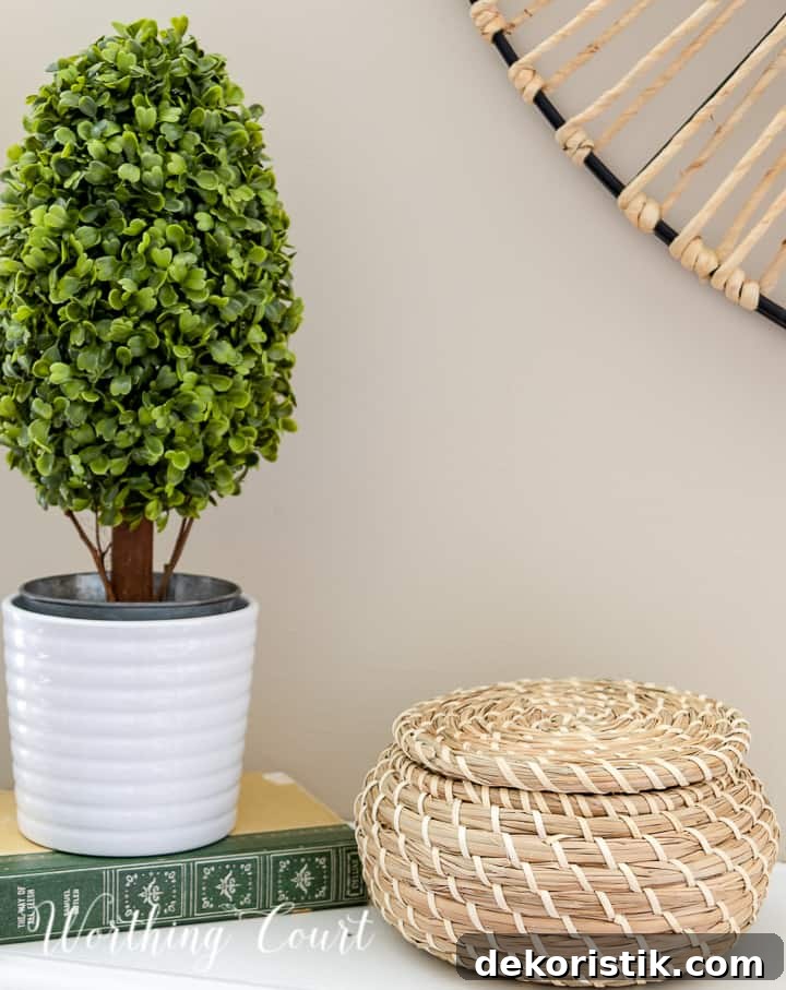 Summer mantel vignette with a candlestick, faux topiary and lidded wicker basket