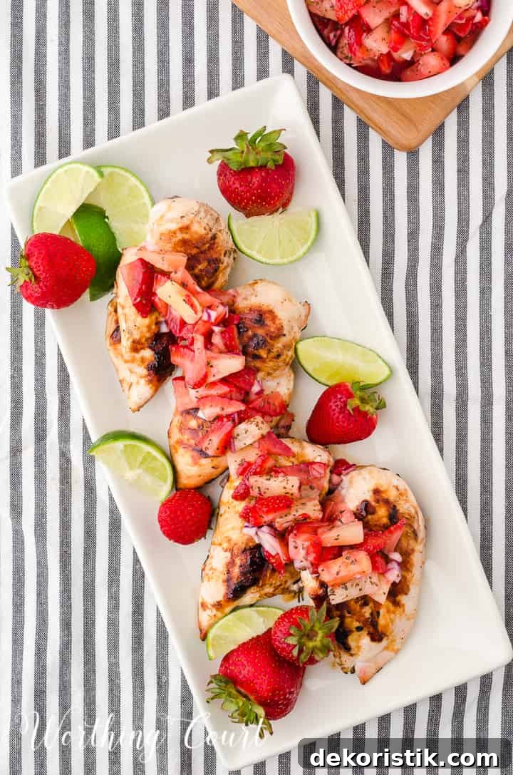 platter of sliced grilled chicken breast topped with strawberry and pineapple salsa