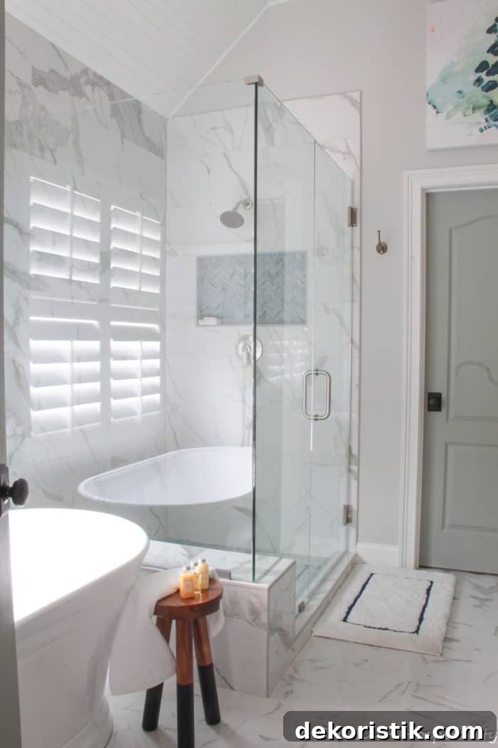 renovated bathroom with white and gray tile, glass shower and white free standing tub