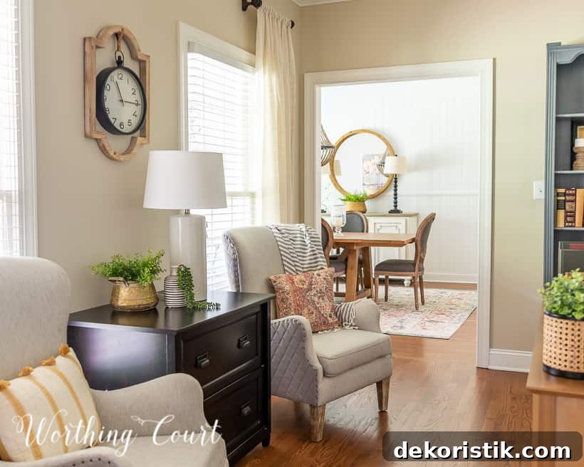 natural colored arm chair beside a black file cabinet with a view into the dining room in the background