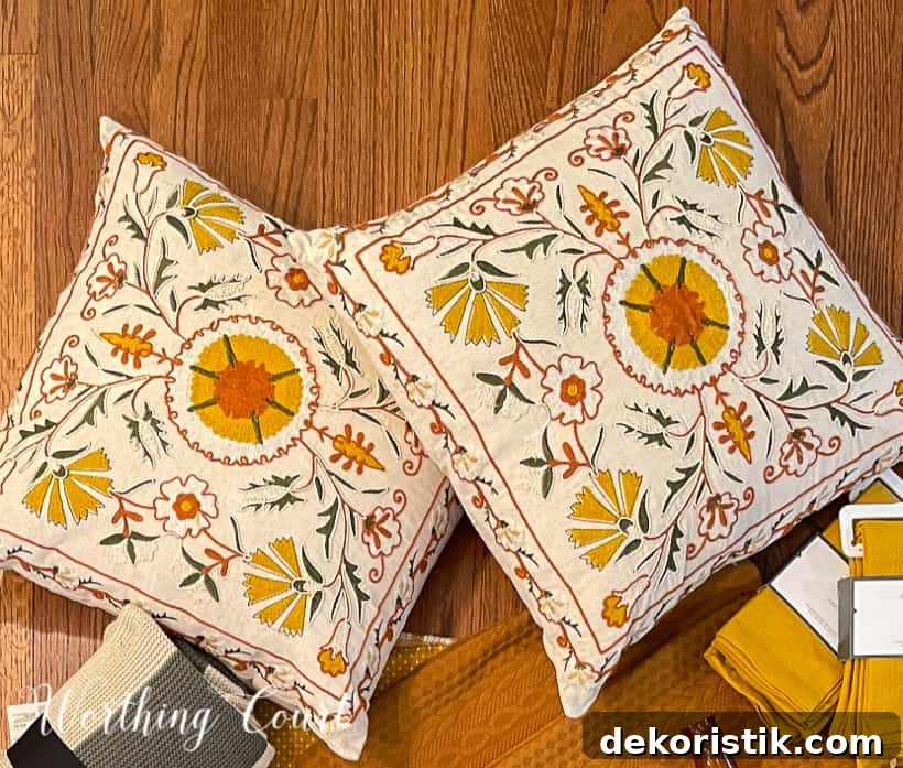 pair of pillows embroidered with yellow, green and deep orange on a cream background