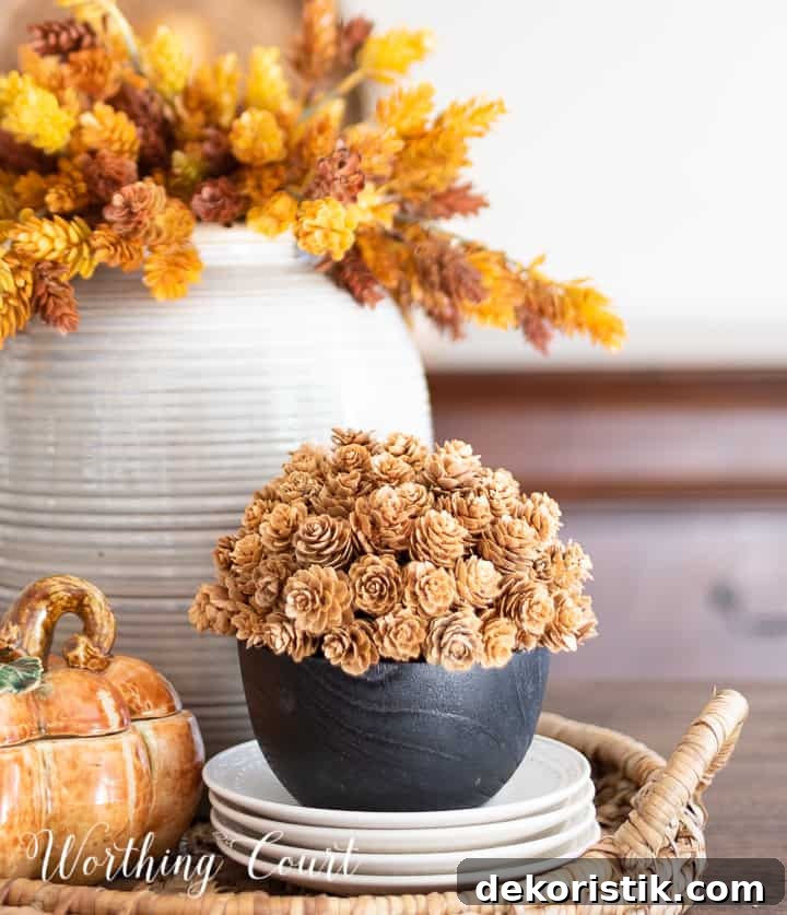 fall centerpiece in a woven tray with a containers filled with faux fall stems and a ceramic pumpkin box