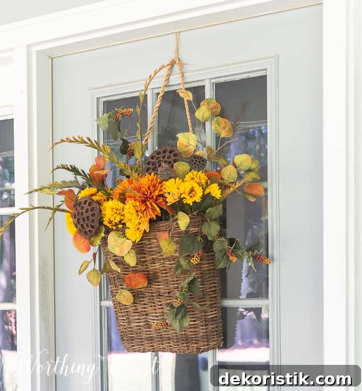 handing basket on gray front door filled with fall colored faux stems