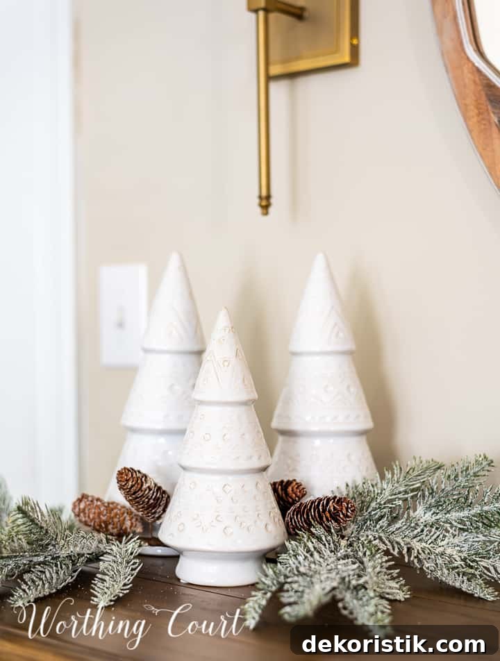 trio of different sized white modern style ceramic Christmas trees and a pair of faux greenery picks