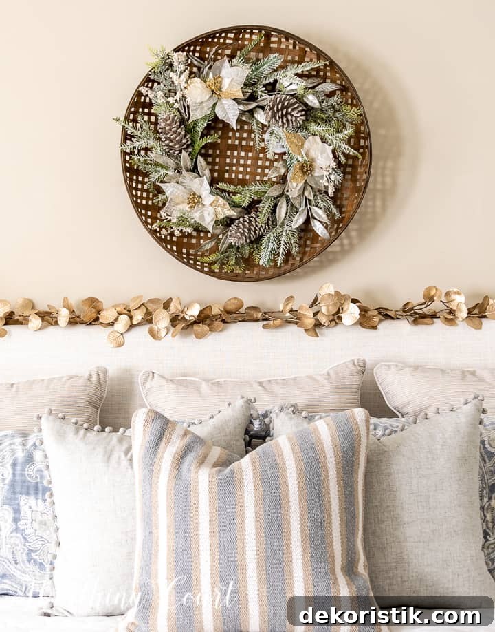 Christmas wreath hanging above upholstered headboard with a gold garland across the top