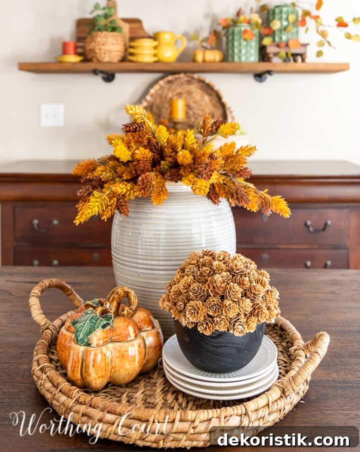 Fall centerpiece in a woven tray with faux stems and a ceramic pumpkin box
