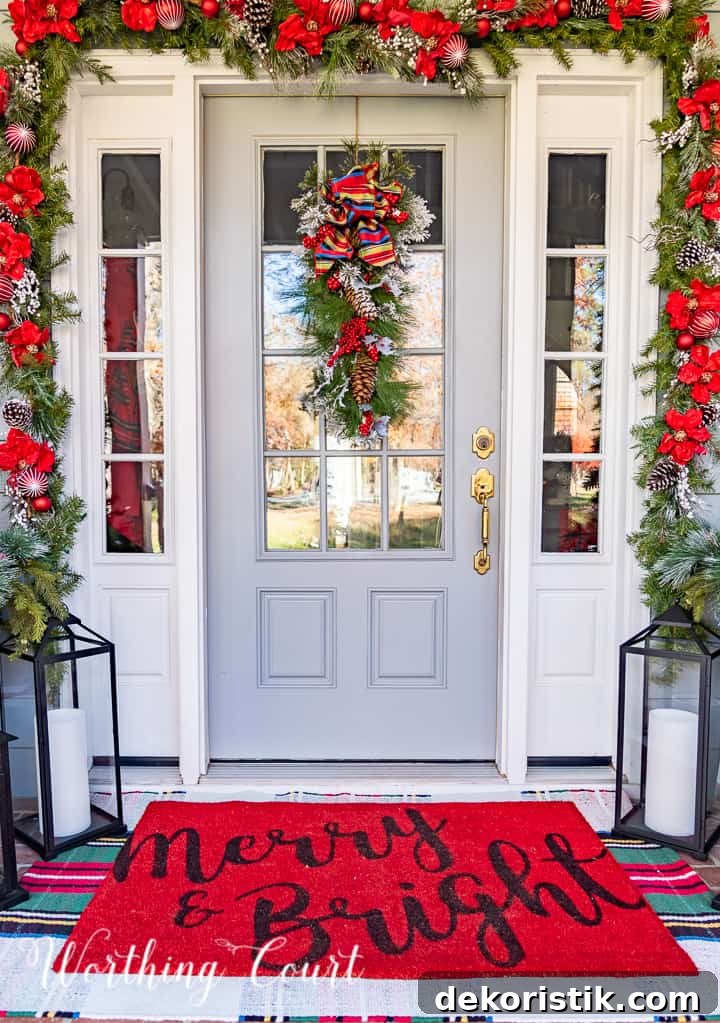 front porch decorated for Christmas with red and white garland, planters, trees, lanterns, rugs and pillows
