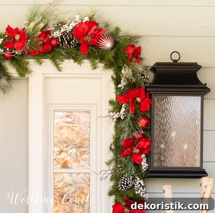 front porch decorated for Christmas with red and white garland, planters, trees, lanterns, rugs and pillows