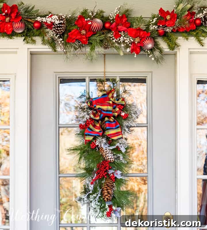 front porch decorated for Christmas with red and white garland, planters, trees, lanterns, rugs and pillows