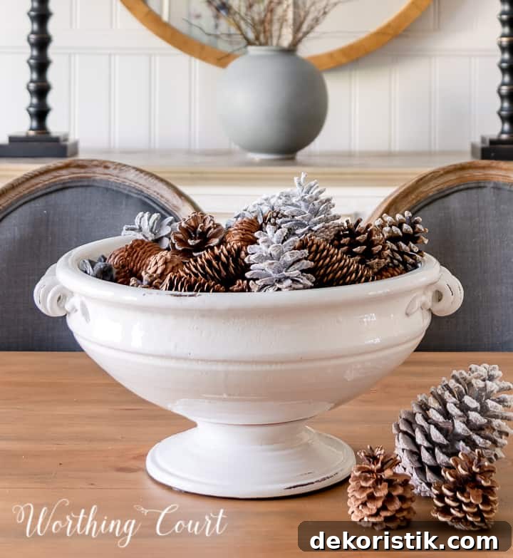 white pedestal bowl filled with pinecones on wood dining table