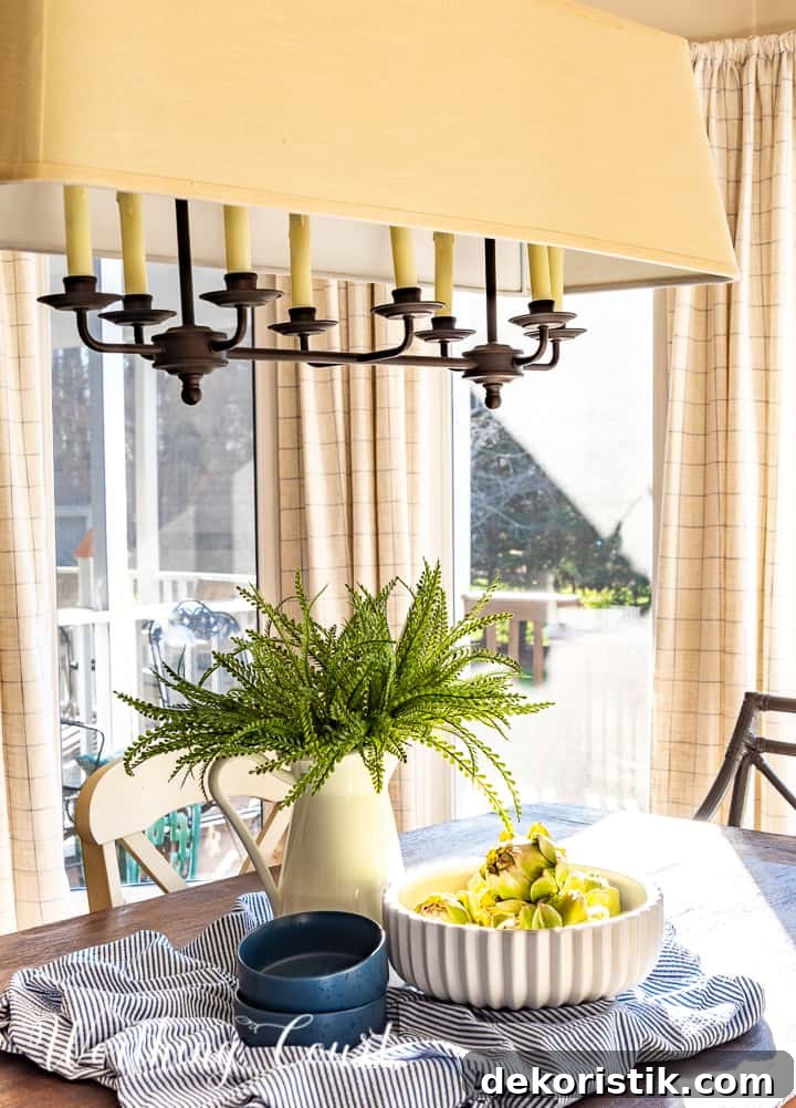 spring centerpiece with blue and white accessories and faux greenery on a dining table