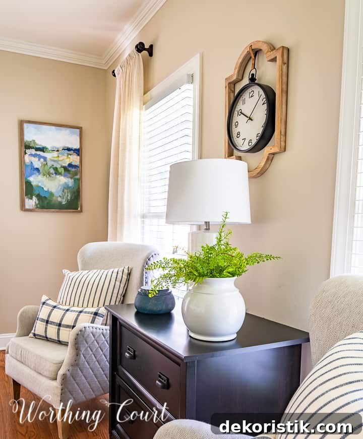 arm chairs flanking black file cabinet with blue and white pillows and artwork